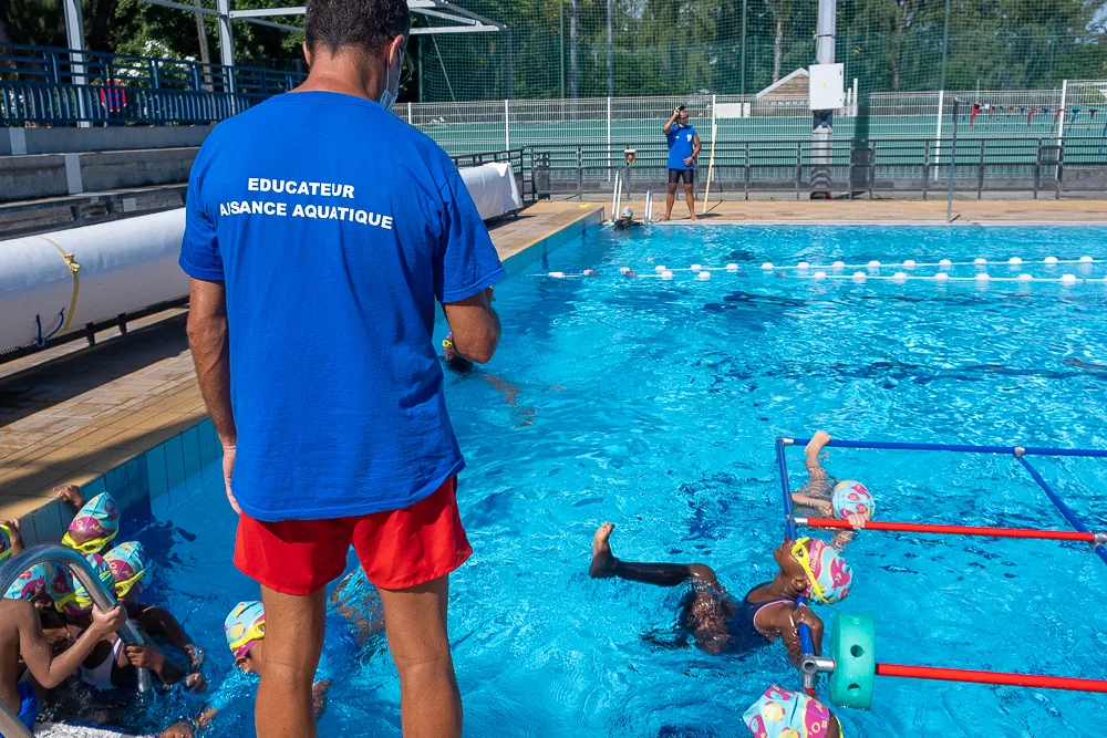 Enfants nageant à la piscine municipale sous la surveillance d’un éducateur d’aisance aquatique